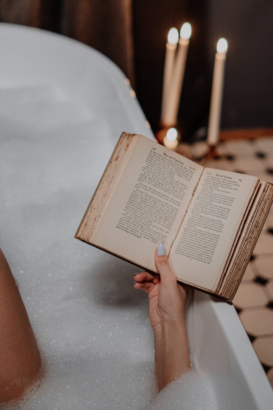 Person Reading Book on White Bathtub